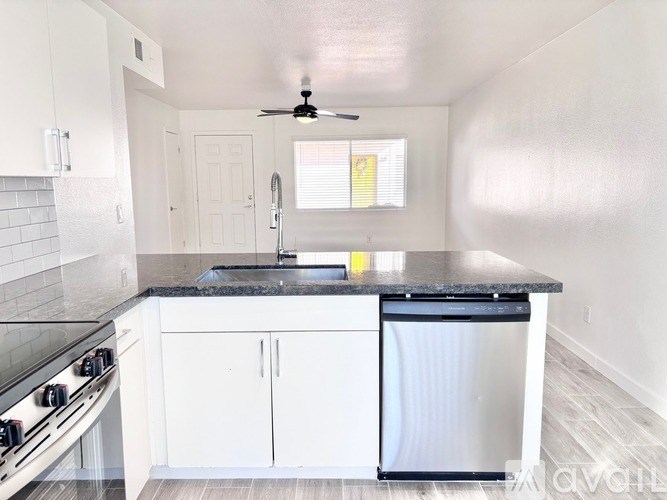 A kitchen with white cabinets and a black countertop.
