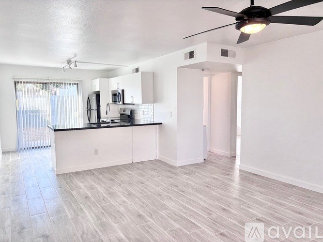 A spacious kitchen with a black ceiling fan and light fixture.