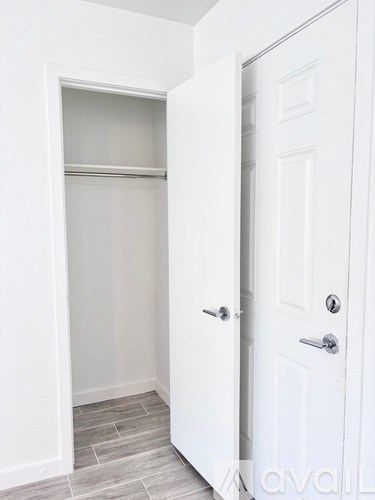 A white door with a silver handle is on the right and a white closet with a shelf is on the left.
