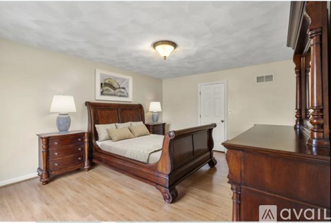 A bedroom with a large bed, a dresser, and a nightstand.
