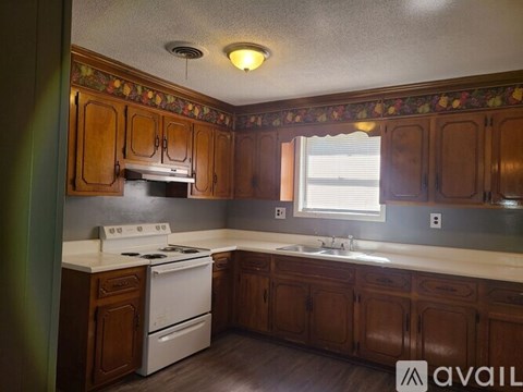 A kitchen with wooden cabinets and a white stove top oven.