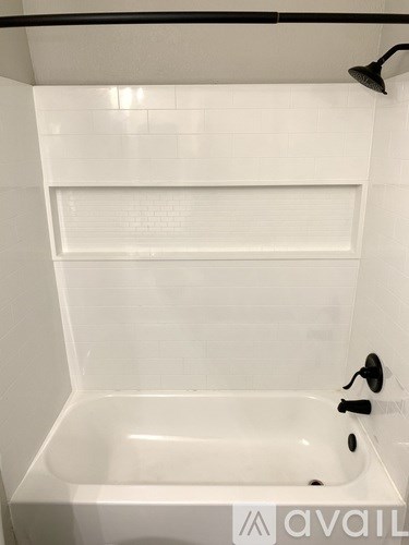 A white bathroom with a tub and a shower head.