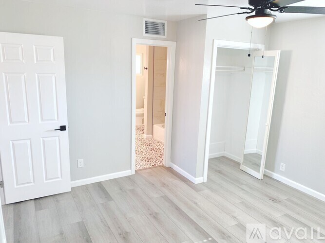 A room with a white door and a mirror on the wall.