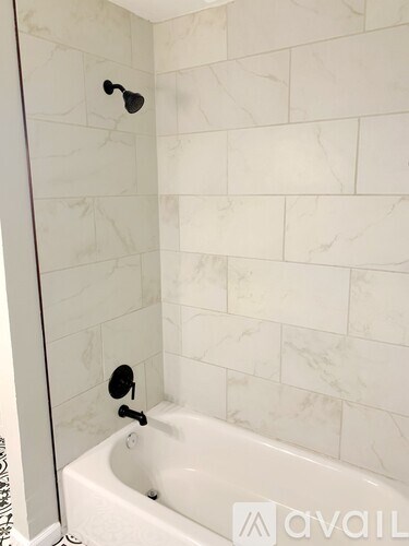 A white bathtub with a shower head and faucet.