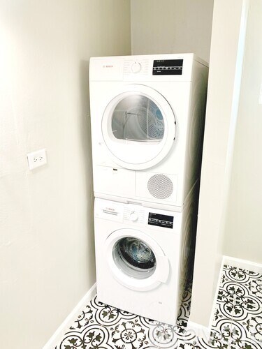 A white front load washing machine with a black and white tiled floor.