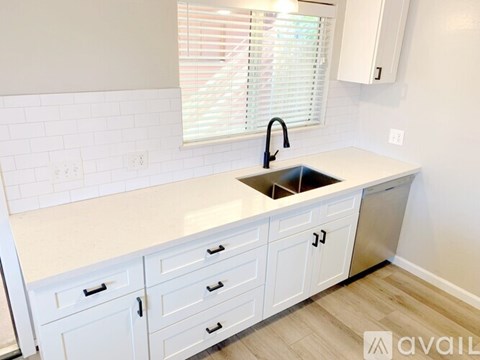 A kitchen with white cabinets and a sink.