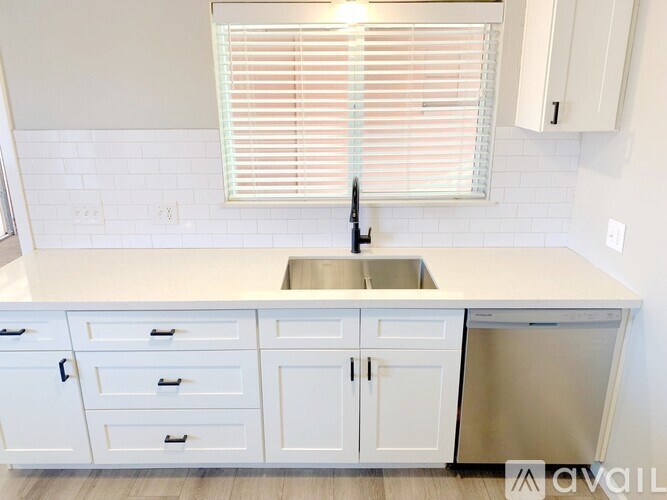 A kitchen with white cabinets and a stainless steel dishwasher.