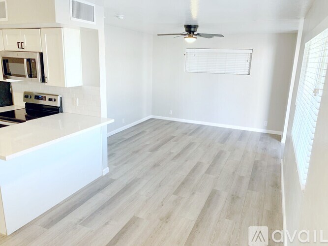 A spacious kitchen with a fan on the ceiling and a stove with a microwave above it.