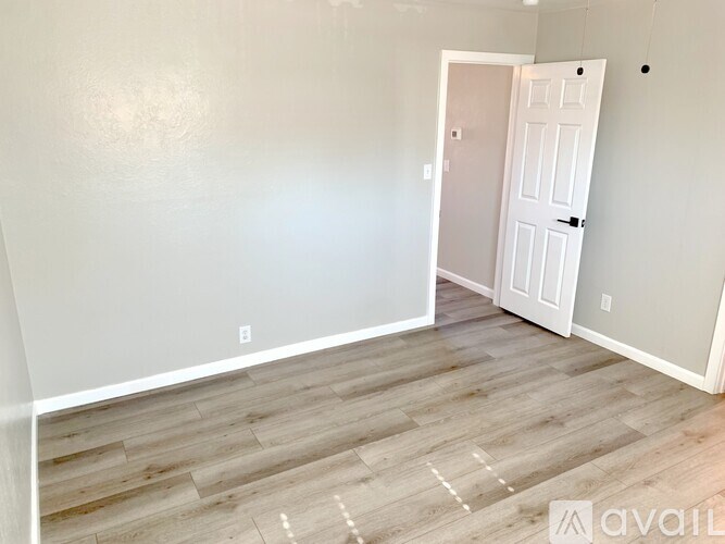 A room with a white door and wooden flooring.
