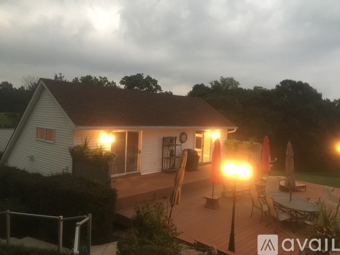 A house with a porch and patio furniture is lit up at dusk.