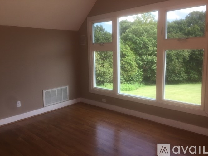 A room with a large window overlooking a green landscape.