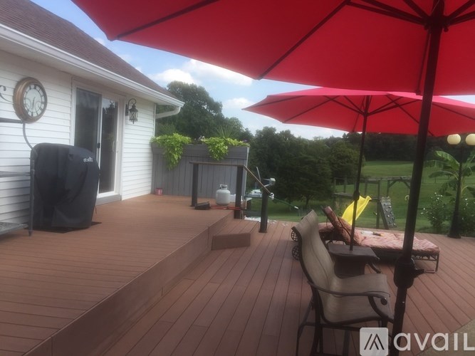 A red umbrella is on a wooden deck.