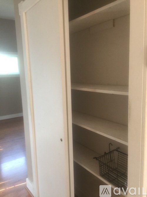 A white pantry cabinet with a wire basket on the shelf.