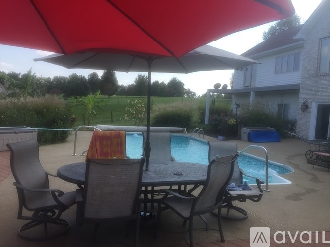A patio with a table and chairs under a red umbrella.