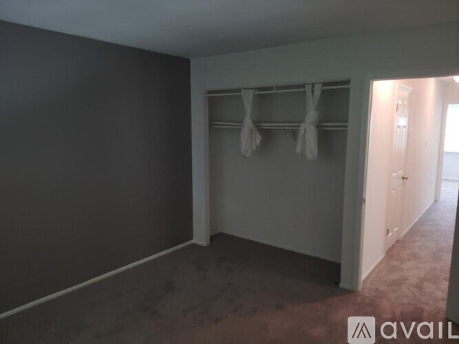 A room with a coat rack and a doorway leading to another room.