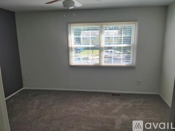 A room with a carpeted floor and a window with blinds.