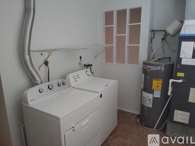 A white dryer is in a room with a wall-mounted heater.