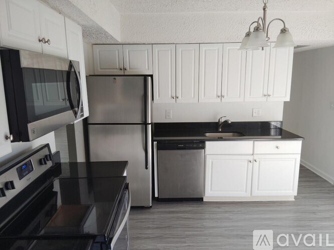 A kitchen with white cabinets and black countertops.