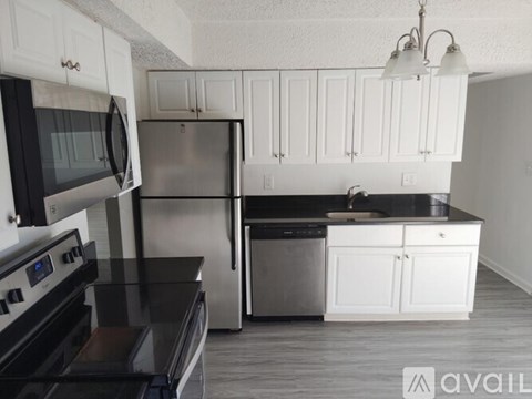 A kitchen with white cabinets and black countertops.