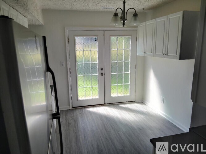 A kitchen with white cabinets and a glass door leading to a backyard.