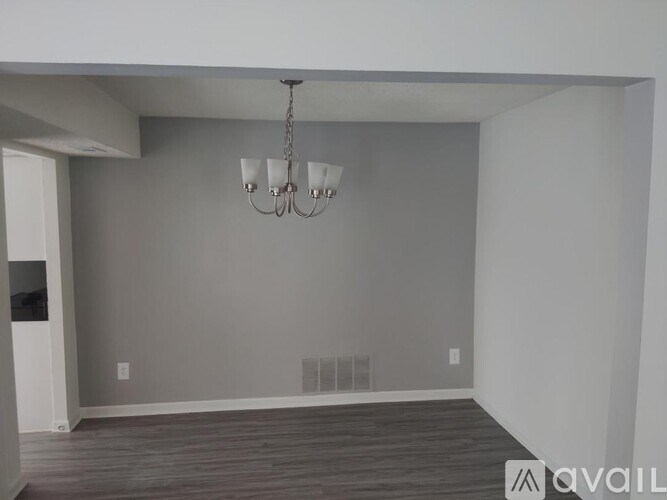 A room with a chandelier and a wooden floor.