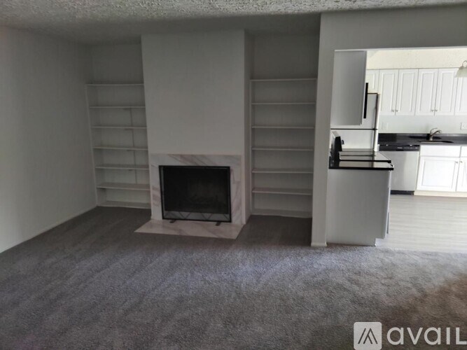 A living room with a fireplace and a kitchen in the background.