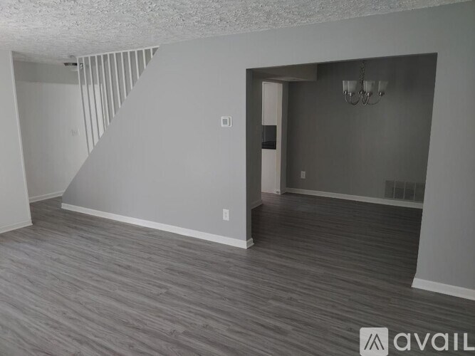 A room with a grey floor and a white wall with a chandelier.