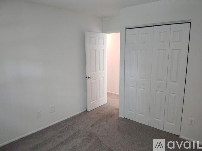 A room with a carpeted floor and two white doors.