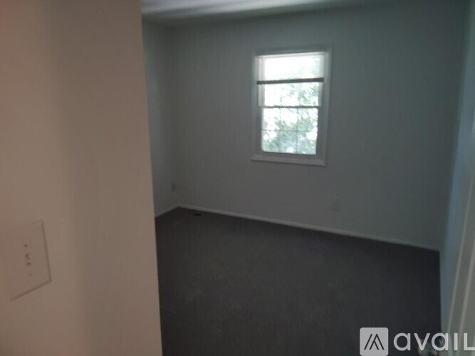 A room with a window and a light switch on the wall.