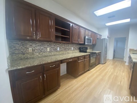 A kitchen with brown cabinets and a granite countertop.