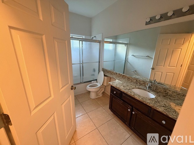A bathroom with a toilet, sink, and mirror.