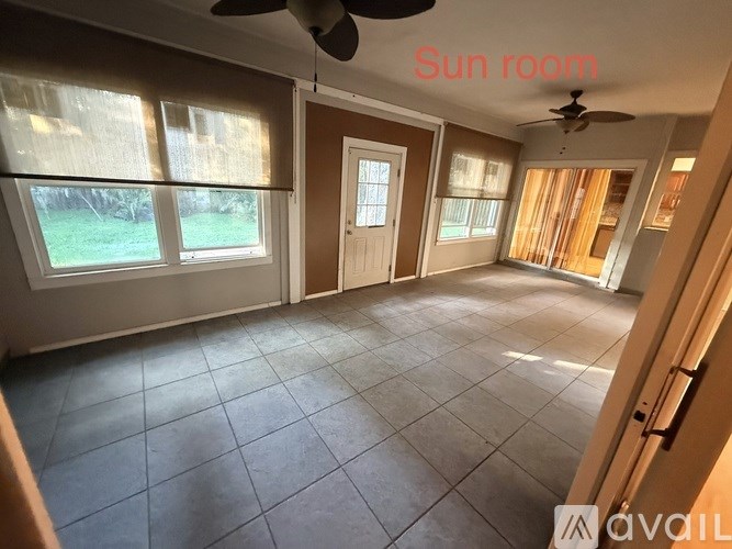 A sun room with a tiled floor and a ceiling fan.