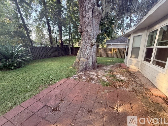 A tree trunk is in the middle of a brick walkway.