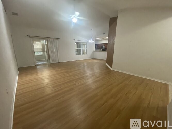 A spacious room with wooden flooring and a ceiling fan.
