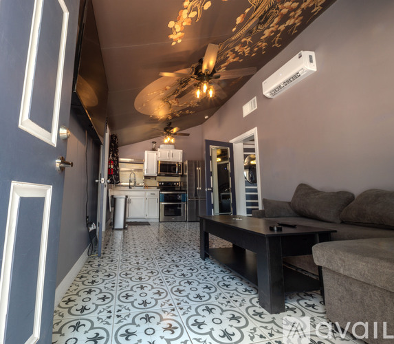 A living room with a couch, coffee table, and a kitchen area in the background.