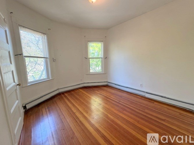 A room with wooden floors and two windows.