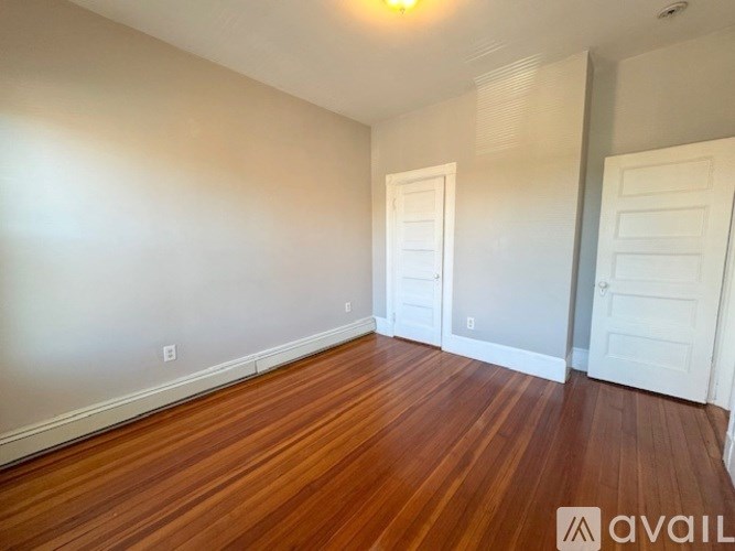 A room with wooden floors and two white doors.