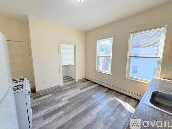 A kitchen with a stove, sink and two windows.