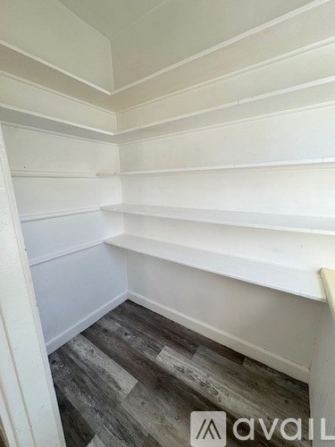 A room with white shelves and wooden flooring.