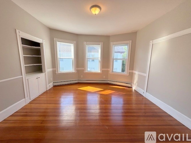 A room with wooden floors and three windows.