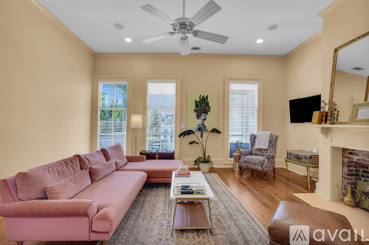 A living room with a pink couch, a fireplace, and a ceiling fan.