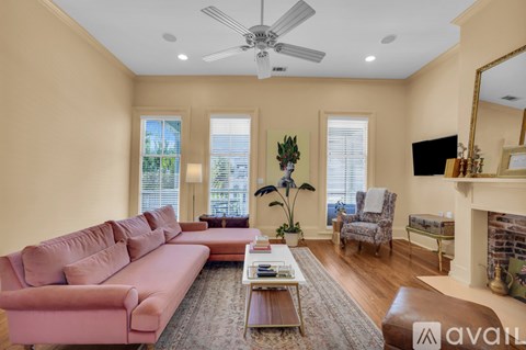 A living room with a pink couch, a fireplace, and a ceiling fan.