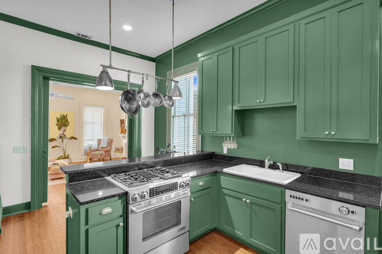 A kitchen with green cabinets and a black countertop.