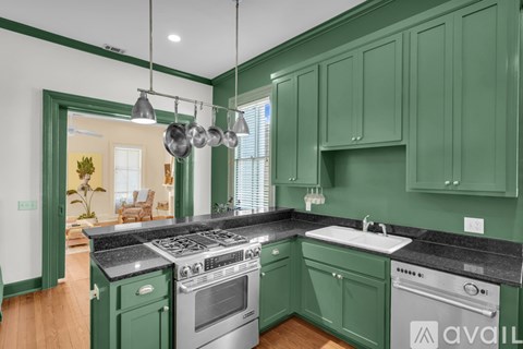 A kitchen with green cabinets and a black countertop.