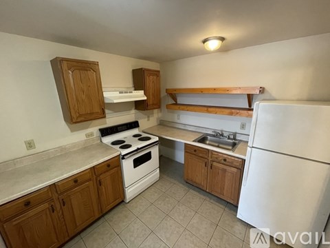 A kitchen with white appliances and wooden cabinets.