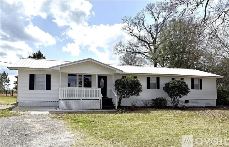 A white house with a porch and a tree in front.