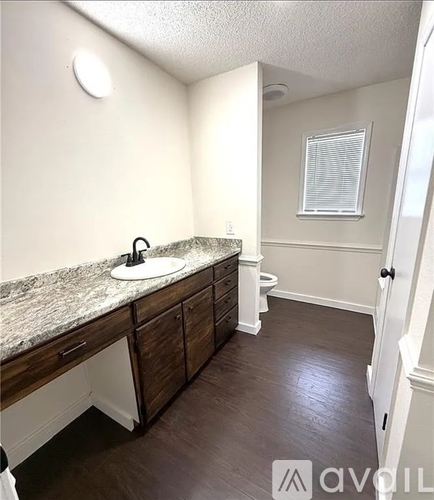 A bathroom with a marble countertop and wooden cabinets.