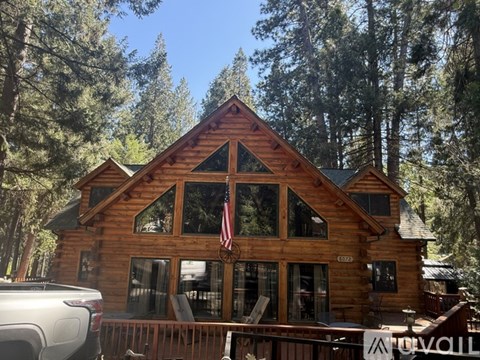A large wooden cabin with a porch and a car parked in front.