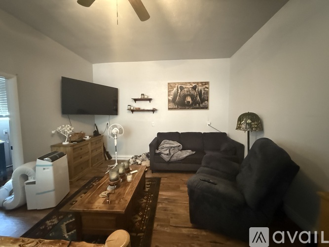 A living room with a black couch and a television on the wall.