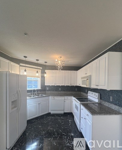 A kitchen with black marble countertops and white cabinets.